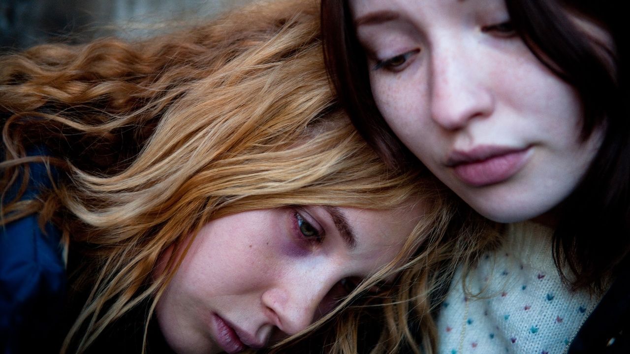Juno Temple is red-eyed and broken down, resting her head on a friend in Magic Magic
