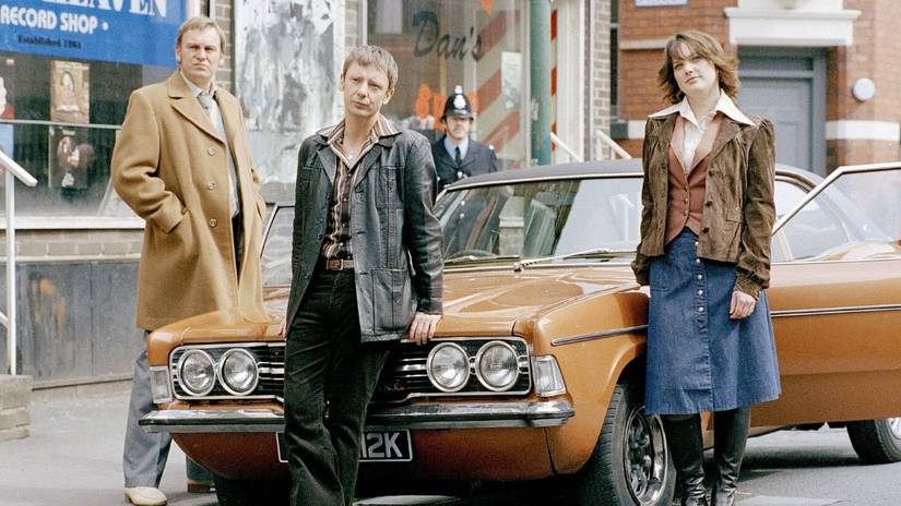 Sam Tyler, Gene Hunt, and Annie Cartwright leaning on the hood of an old 70s car in Life on Mars.