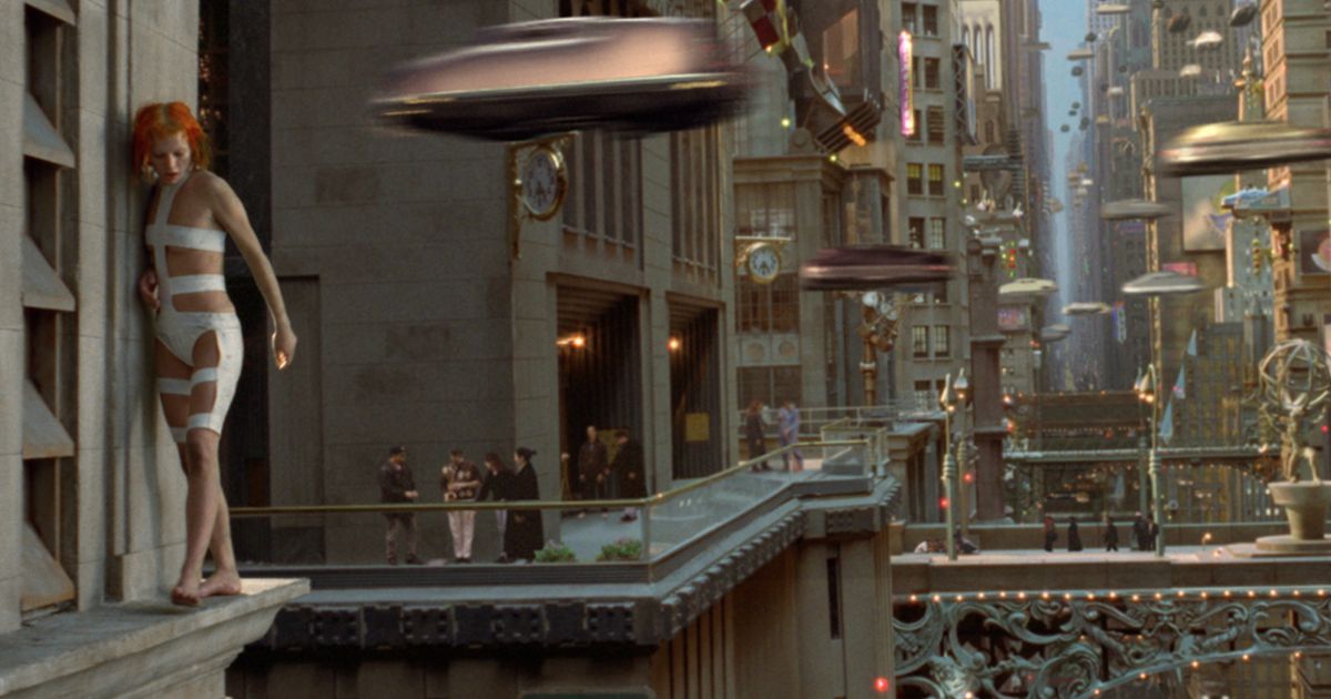 Milla Jovovich walks on city ledge.