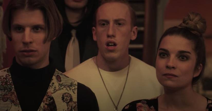 Group of people stand together inside of a dimly lit home.