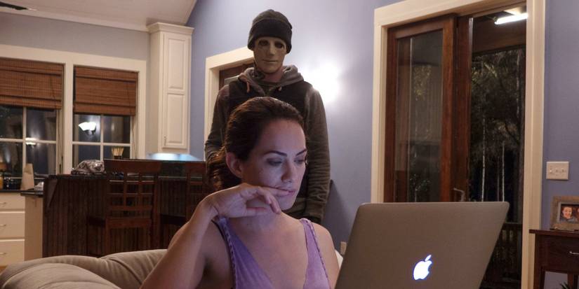 John Gallagher Jr. as the killer preparing to attack Kate Siegel as Maddie in Hush 