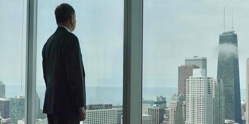 A man stands before a window looking over the Chicago skyline in The Men Who Stole the World (2018).