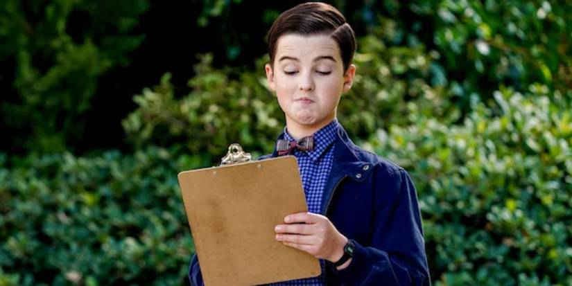Iain Armitage as Sheldon Cooper writing on a clipboard while wearing fancy clothes in Young Sheldon