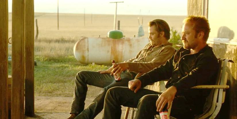 Chris Pine as Toby and Ben Foster as Tanner, sitting on a porch and drinking beers as the sun sets