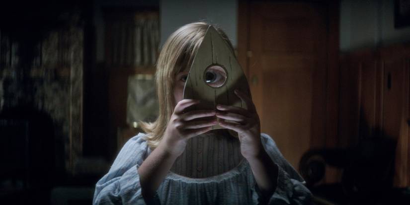 Lulu Wilson uses the Ouija device to see through it in the film Ouija: Origin of Evil