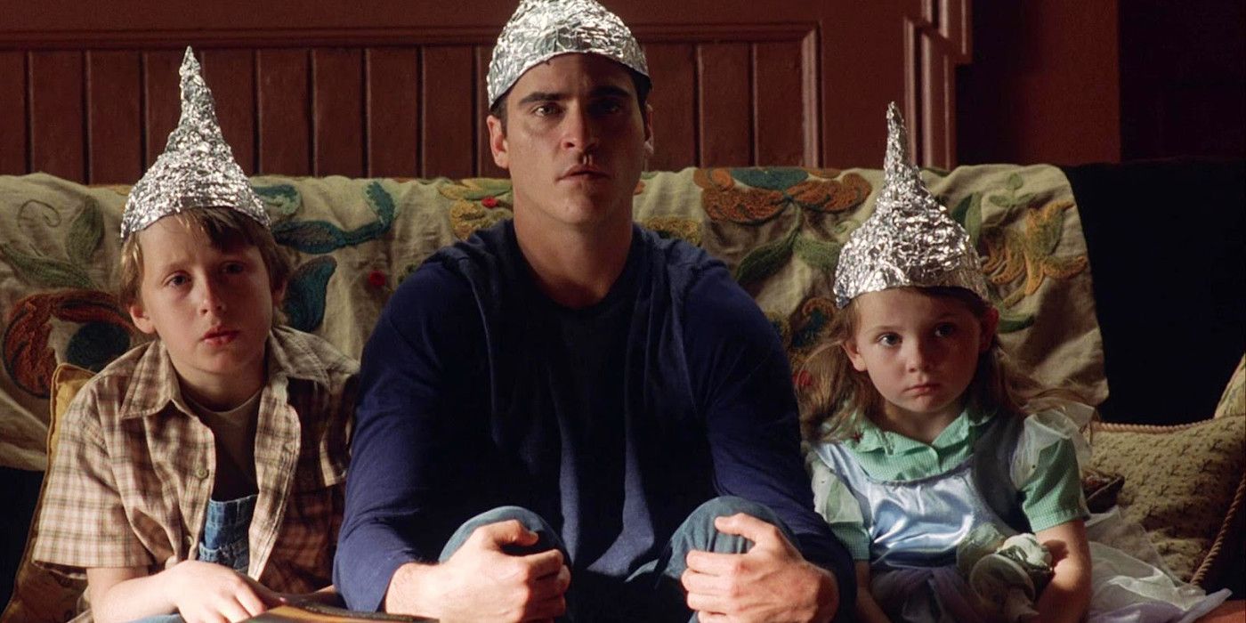 Rory Culkin, Joaquin Phoenix, and Abigail Breslin sitting on a couch wearing tin foil hats in Signs.