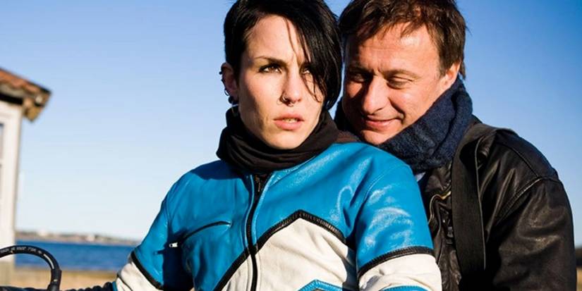 Noomi Rapace as Lisbeth and Michael Nyqvist as Mikael, astride a motorcycle 
