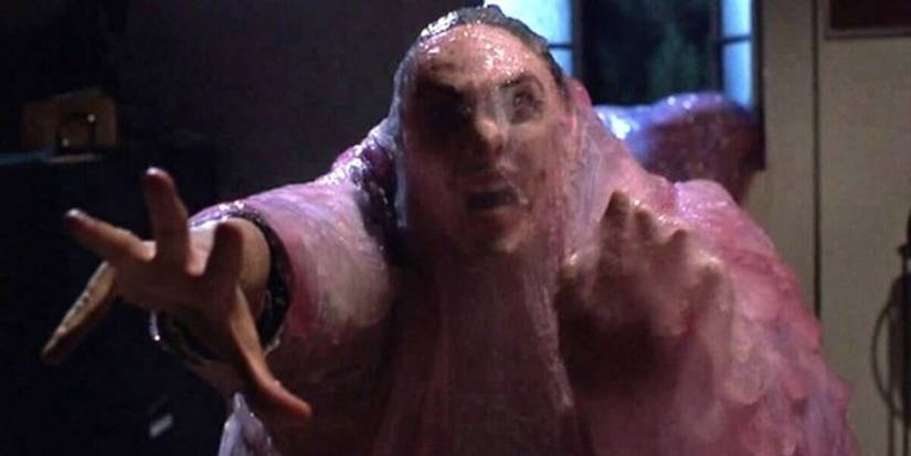 A person trapped in a pink and purple goo reaching out for help in The Blob