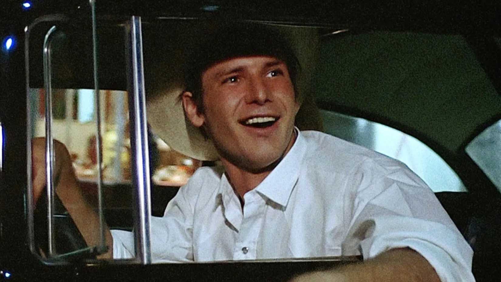 harrison ford laughs as he drives in the film american graffiti
