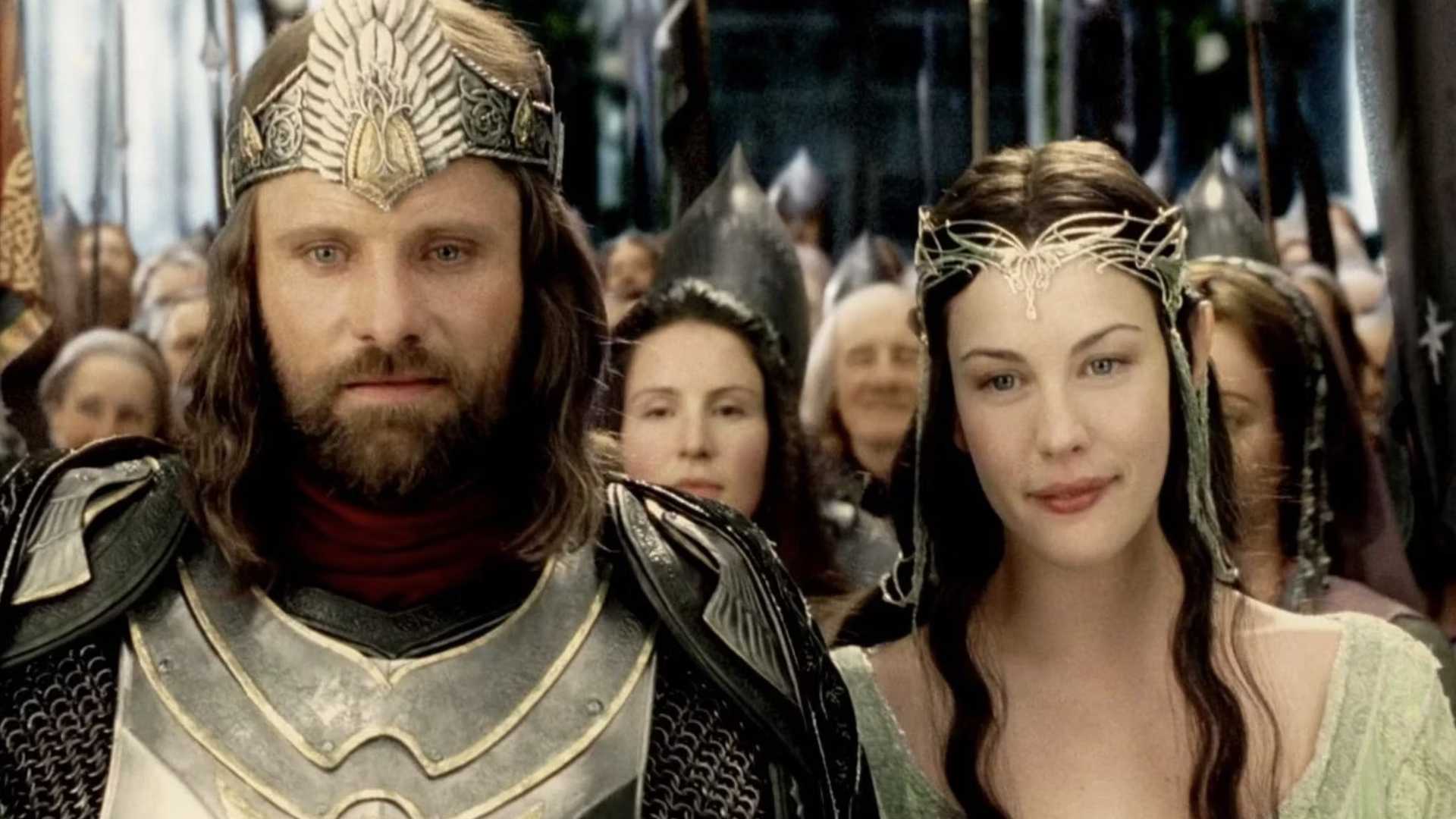 Aragorn and Arwen stand together in Lord of the Rings wearing their crowns with other elves