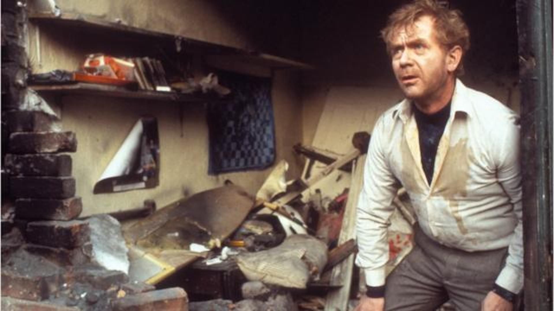 A man climbing out of his destroyed house with his wall blown open in Threads
