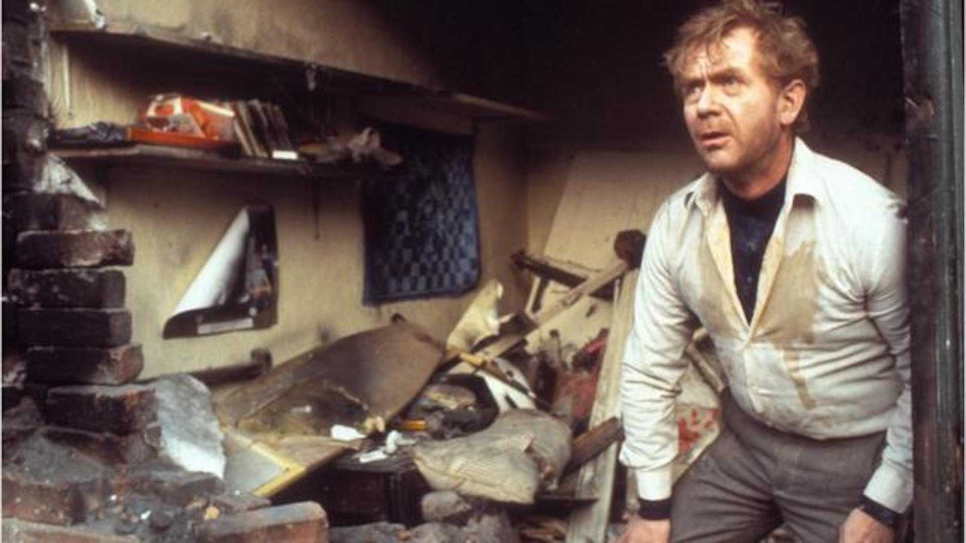 A man climbing out of his destroyed house with his wall blown open in Threads