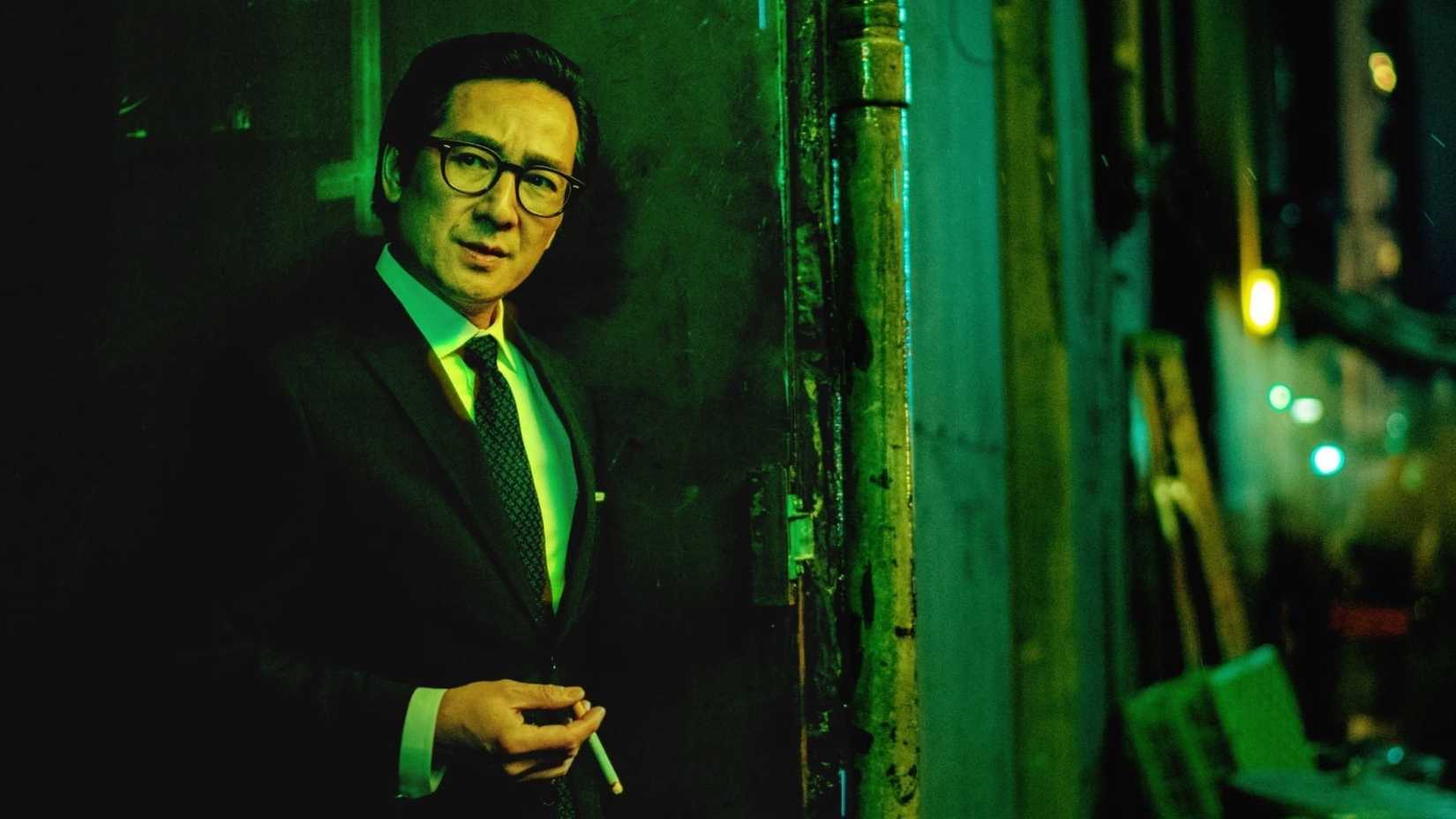 Ke Huy Quan in Everything Everywhere All at Once wearing a suit and smoking outside