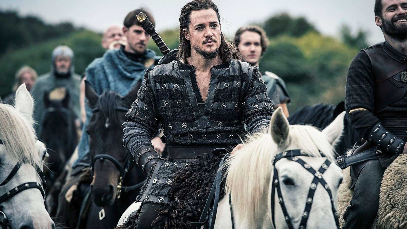 Alexander Dreymon in The Last Kingdom. riding a white horse in front of a group of soldiers