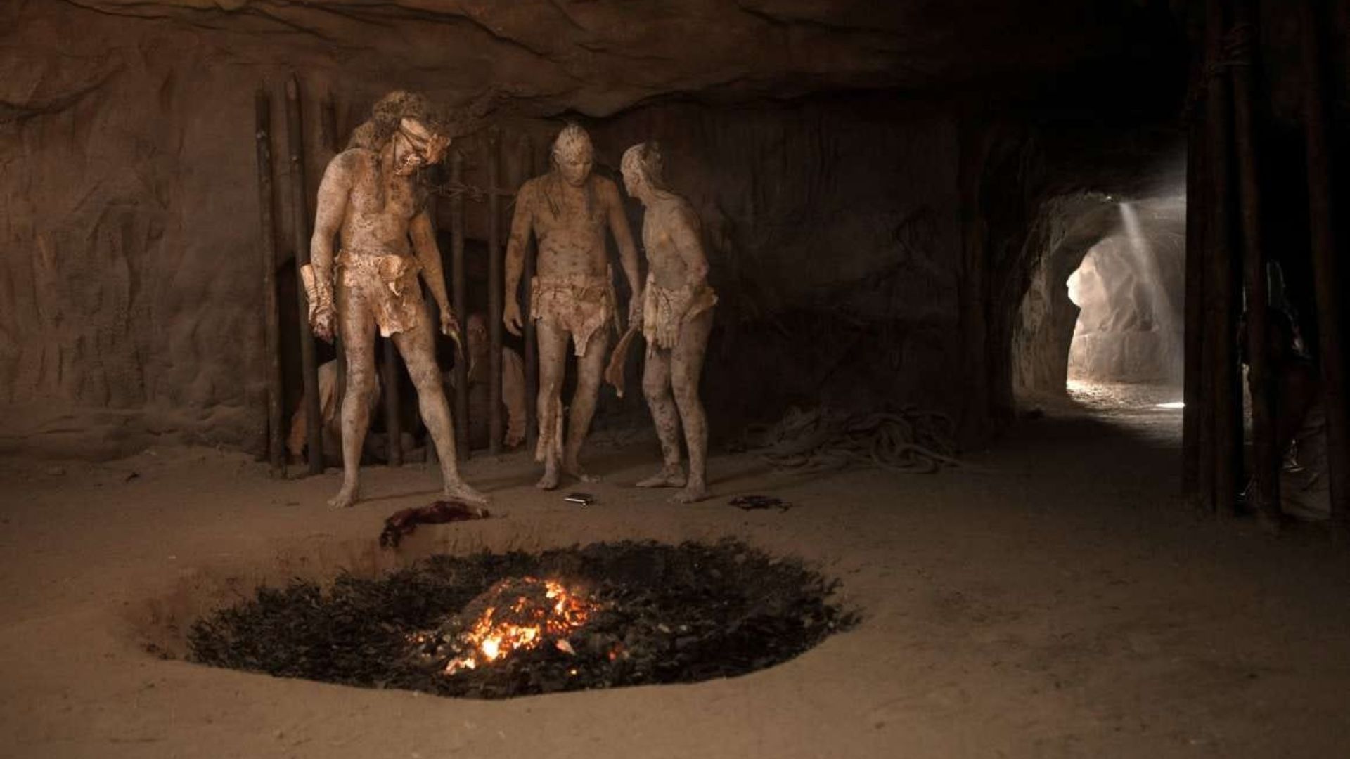 three cannibals around a fiery pit inside a cave in the film bone tomahawk