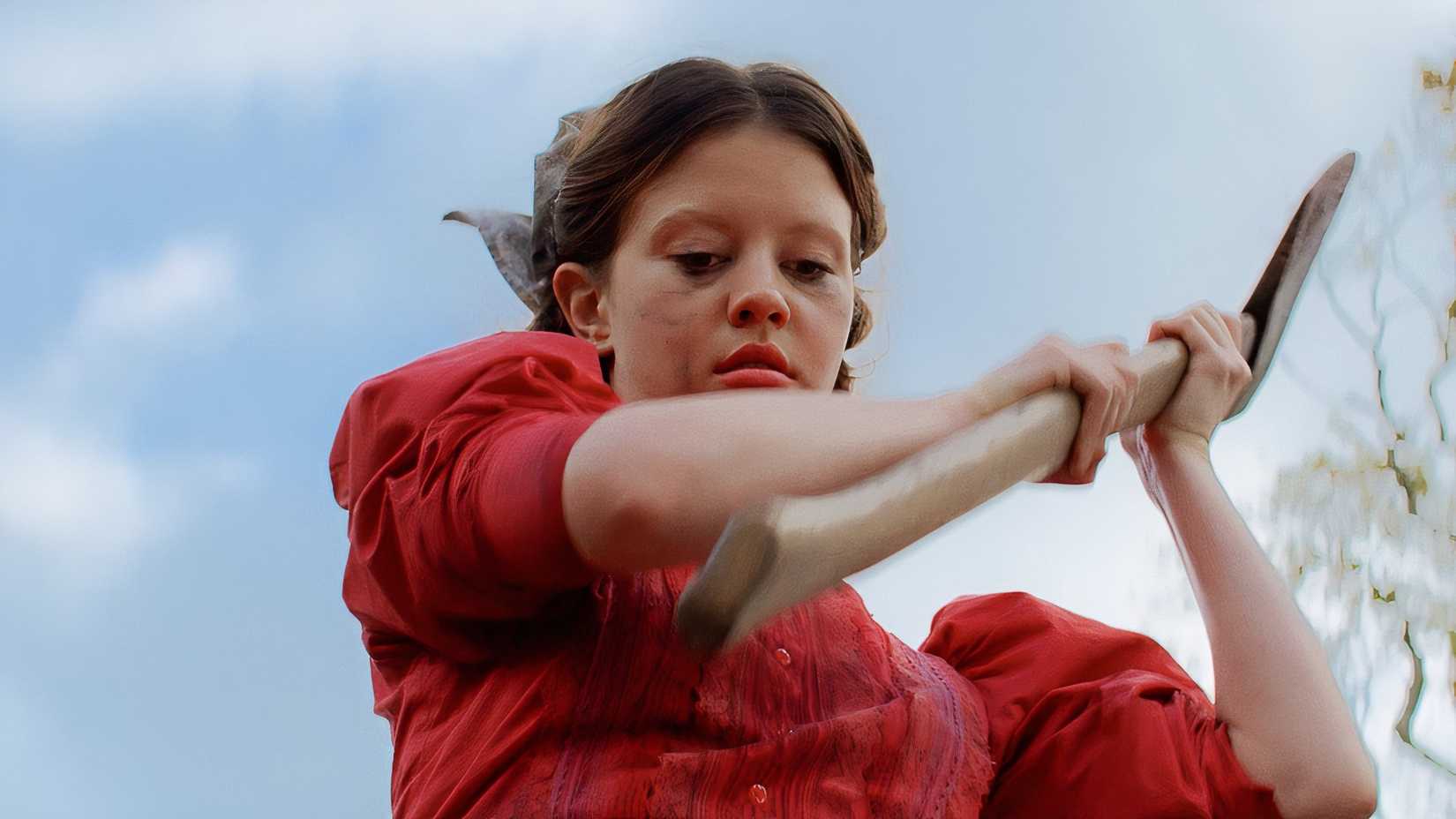 Pearl (Mia Goth) holding an axe about to swing down on Mitsy in Ti West's Pearl.