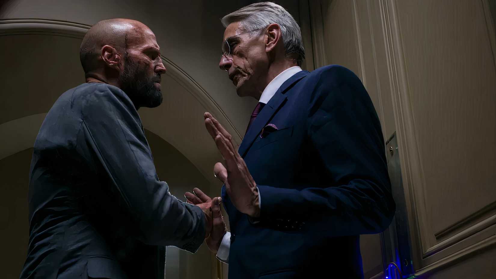 Jason Statham faces Jeremy Irons who holds his hands up in the film the beekeeper