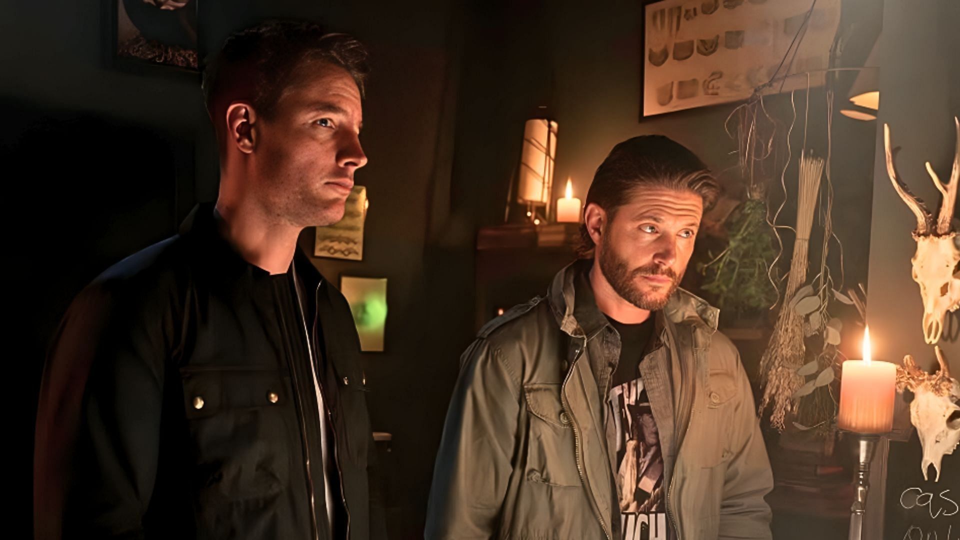 Justin Hartley and Jensen Ackles in Tracker talking to someone in a dark room.