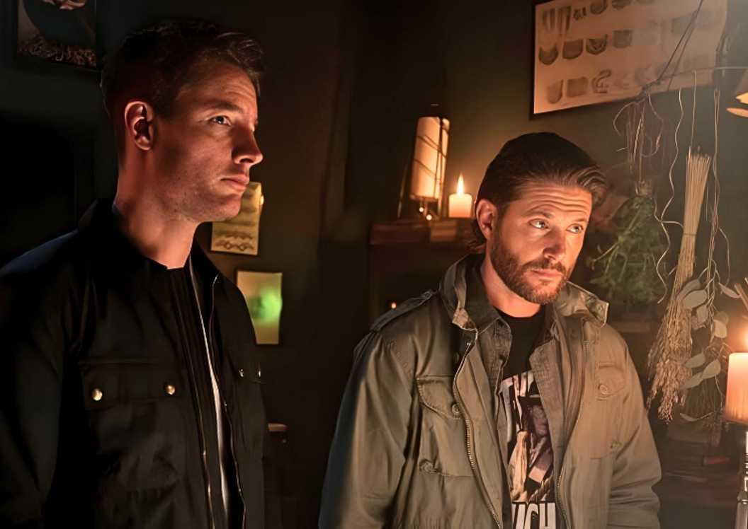 Justin Hartley and Jensen Ackles in Tracker talking to someone in a dark room.