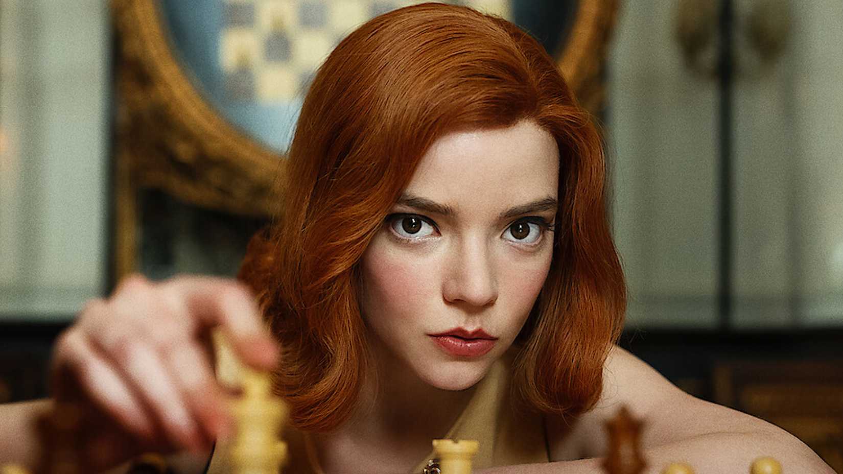 Anya Taylor-Joy in The Queen's Gambit moving a chess piece and looking toward the audience