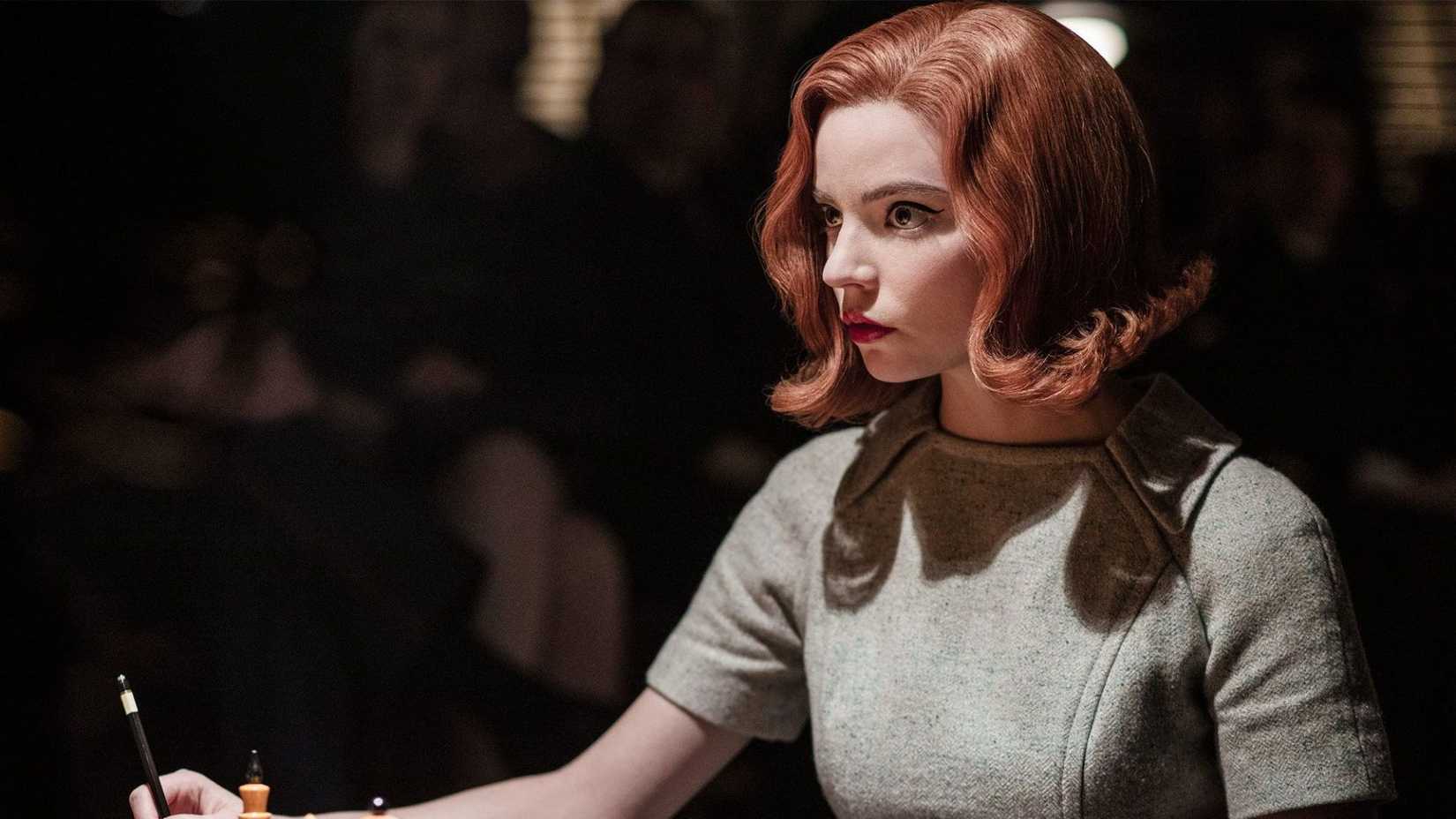 Beth playing chess in a dark room, staring at her opponent, in The Queen's Gambit.