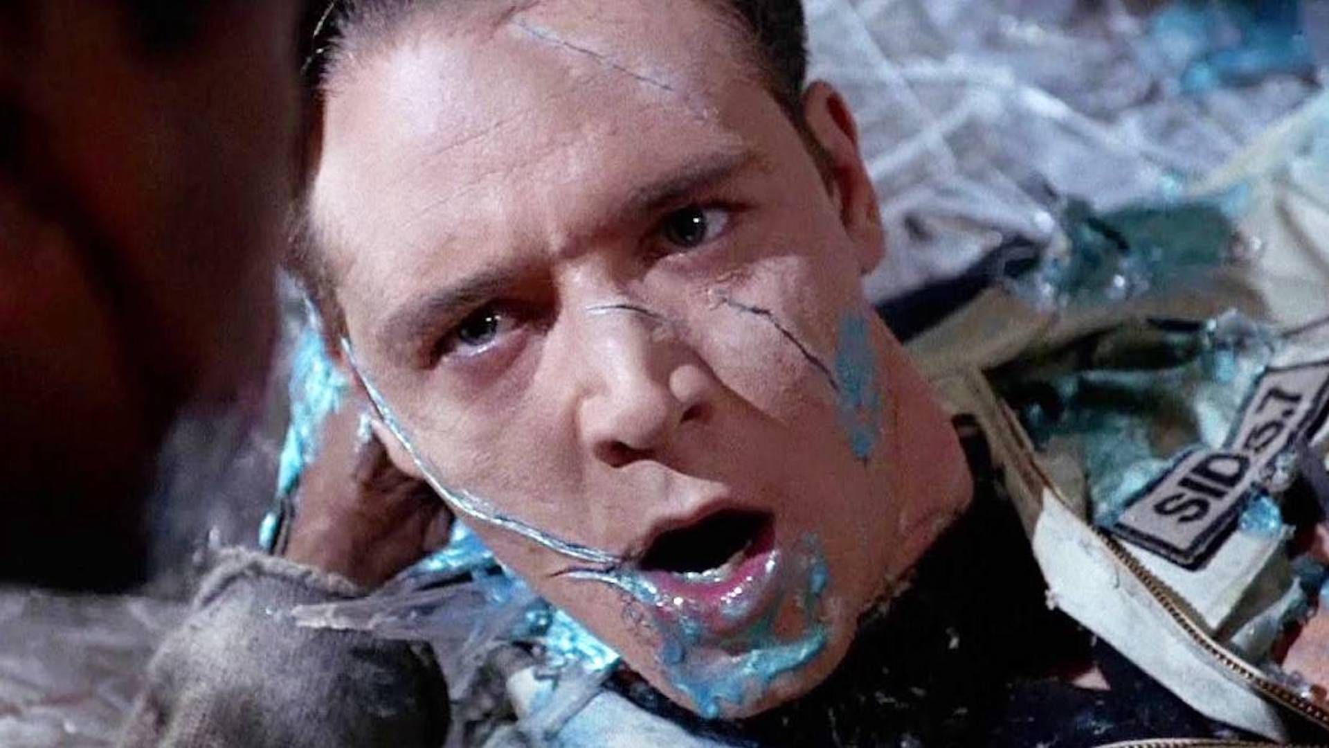 Russell Crowe with blue goo on his face looking up at Denzel Washington in Virtuosity