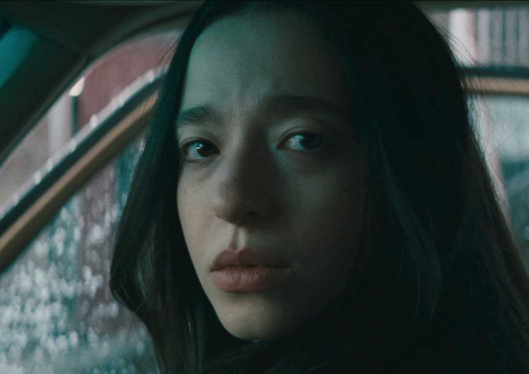 Mikey Madison in Anora in a car looking to the side directly toward the camera