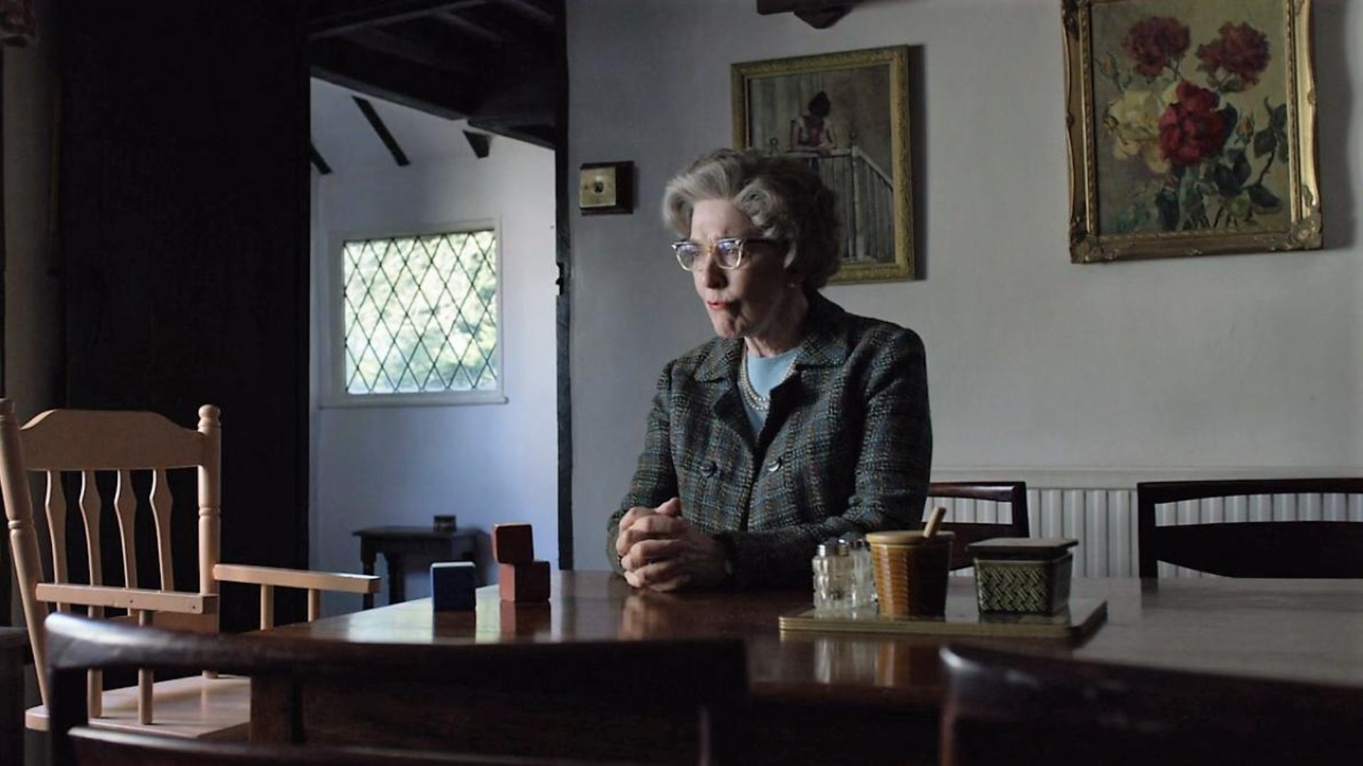Patricia Hodge as Ursula Thorpe sitting at a desk with her hands clasped in A Very English Scandal