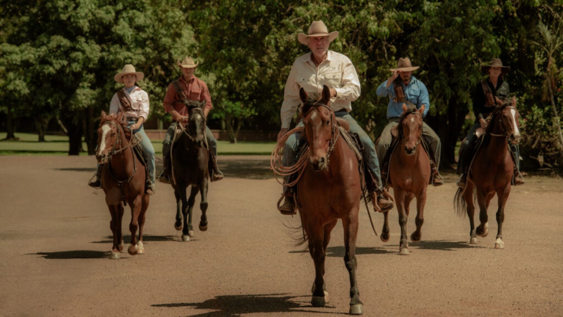 A group of people travel by horseback in Territory