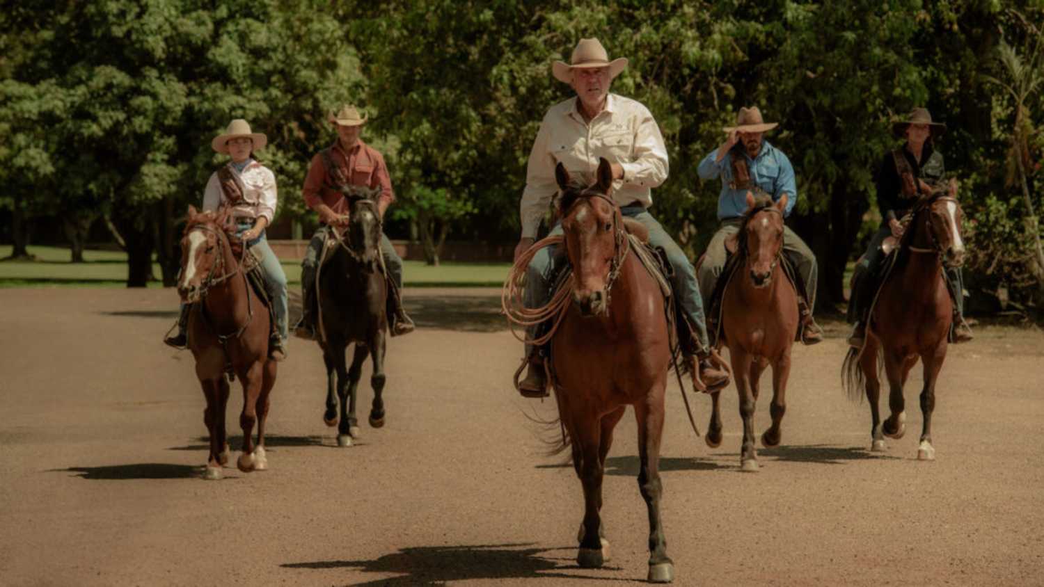 A group of people travel by horseback in Territory