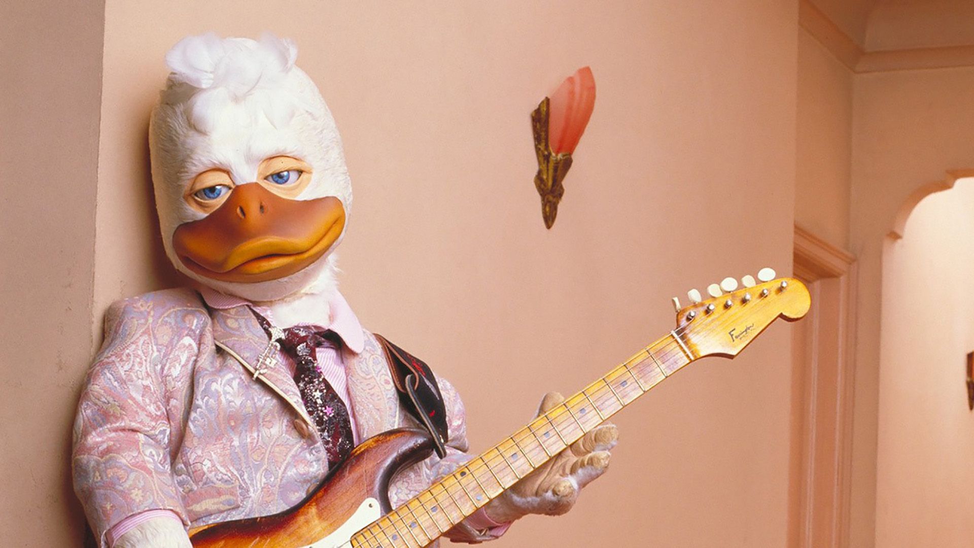 Howard leaning back seductively holding a guitar in Howard the Duck.