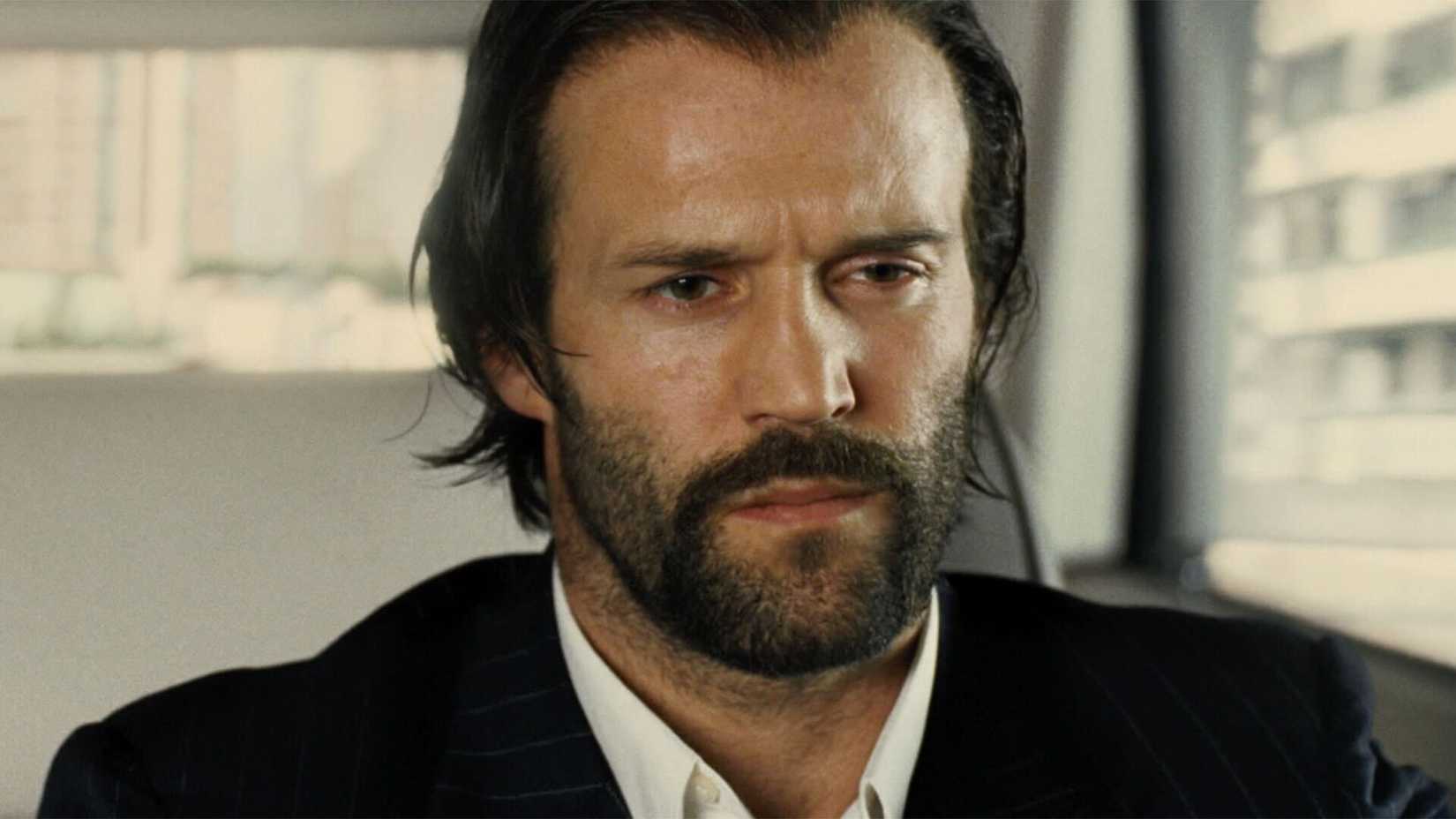 Jason Statham driving a car with a frustrated look in Revolver