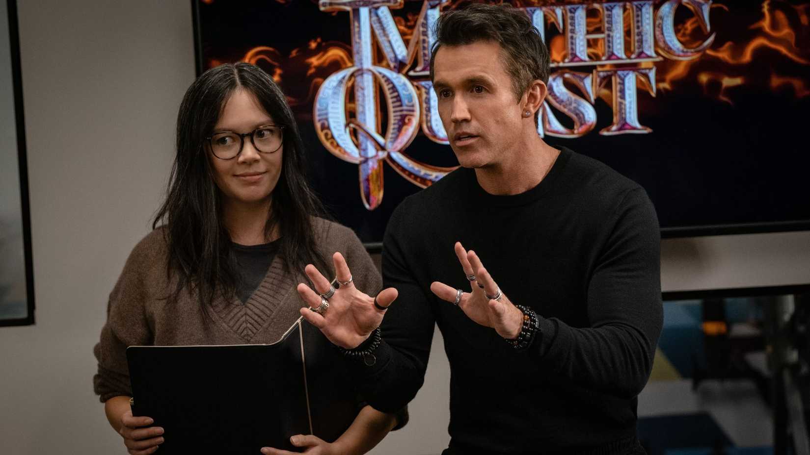 Ian with his hands out as Poppy stands next to him in Mythic Quest.