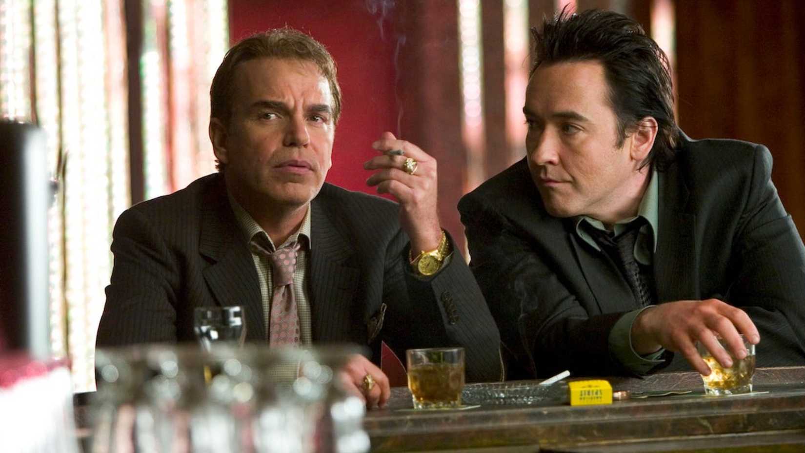 Billy Bob Thornton smokes with John Cusack at the bar in the movie The Ice Harvest