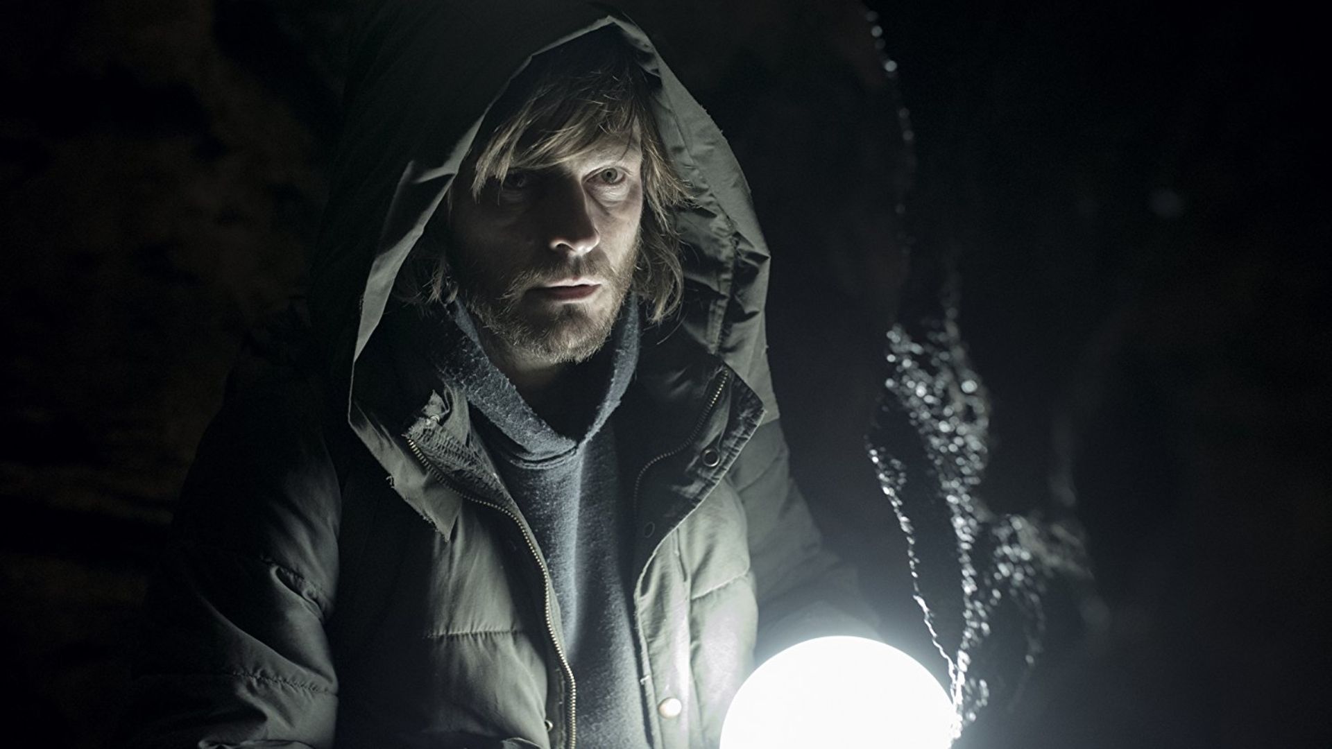 A man holds a glowing light in Dark