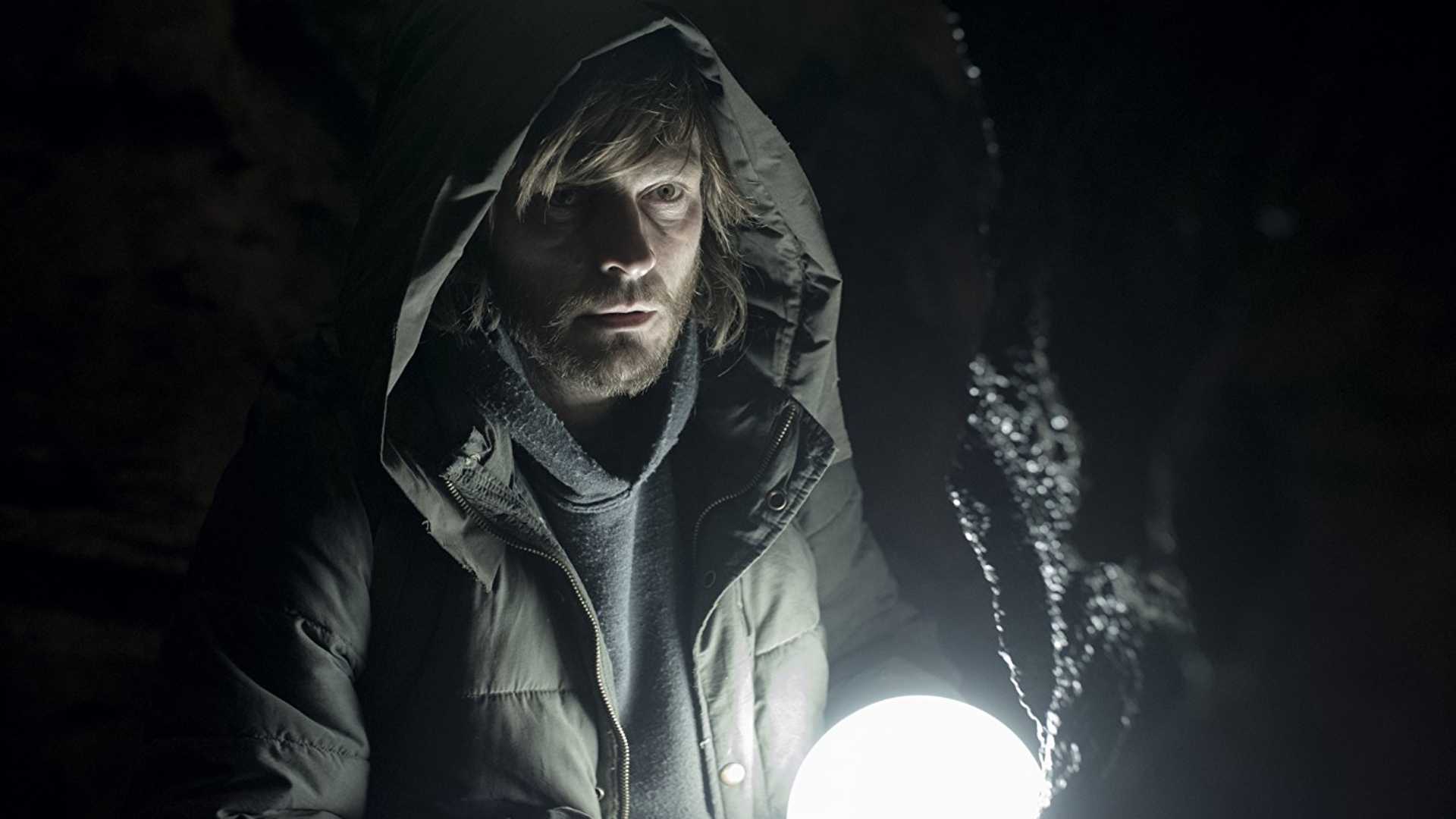 A man holds a glowing light in Dark