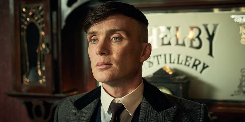 Cillian Murphy as Tommy Shelby staring ahead while leaning against the mantel in the Shelby distillery in Peaky Blinders.