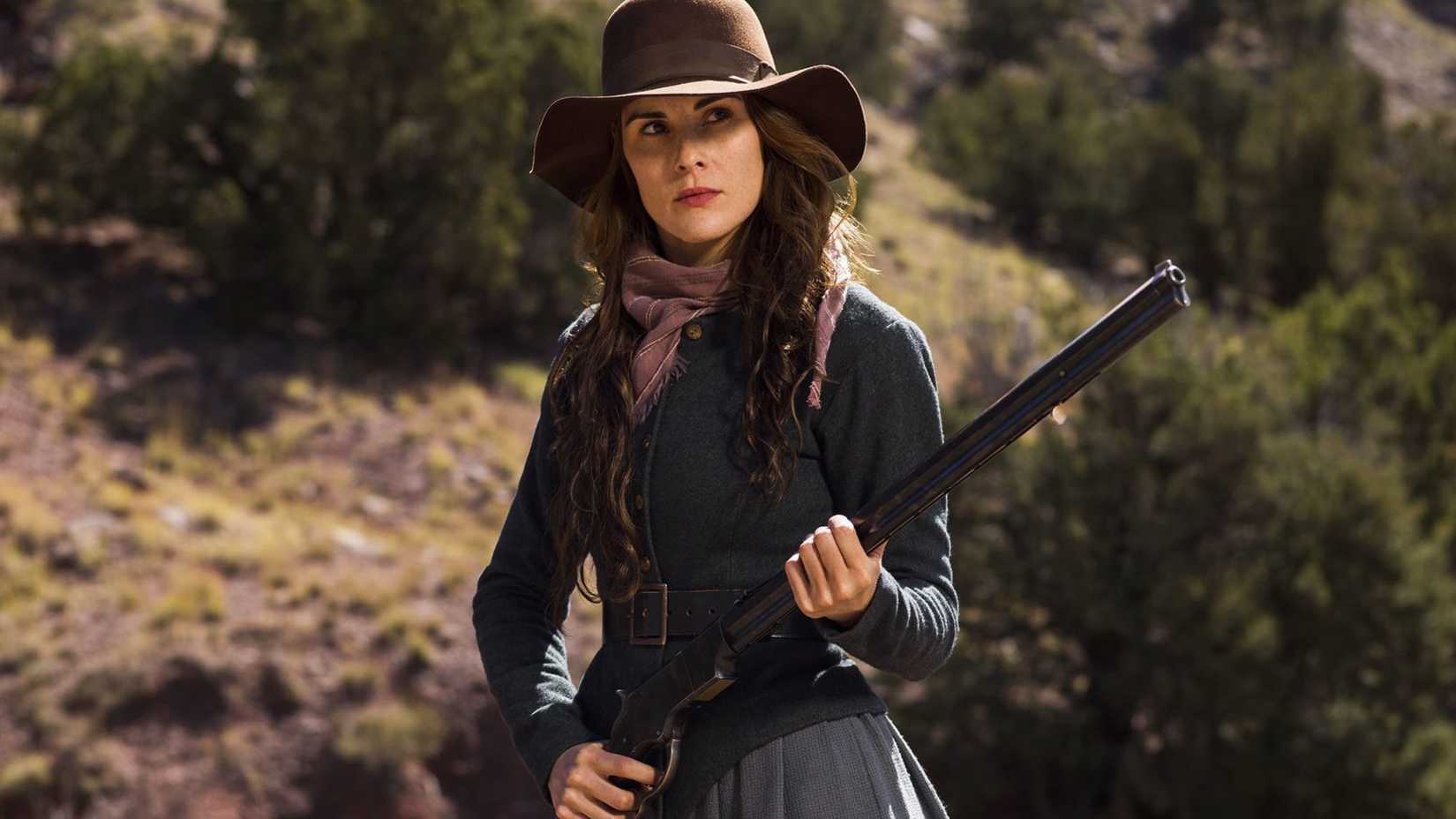 A woman holding a gun outside in Godless