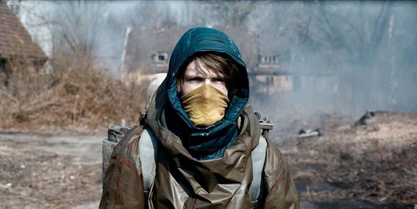 Louis Hofmann as Jonas wearing a mask and hoodie as he treks through a woodland in Dark.