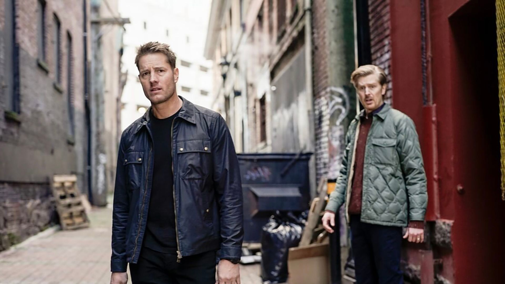 Colter standing on the street, Logan behind him in Tracker.