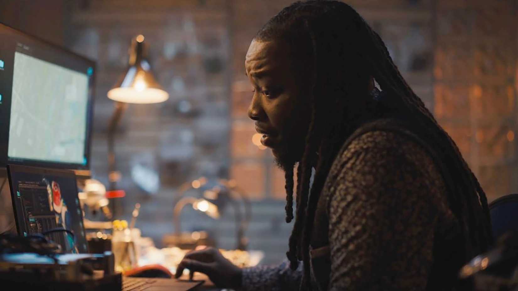 Randy sitting at Bobby's desk in front of his computer in Tracker