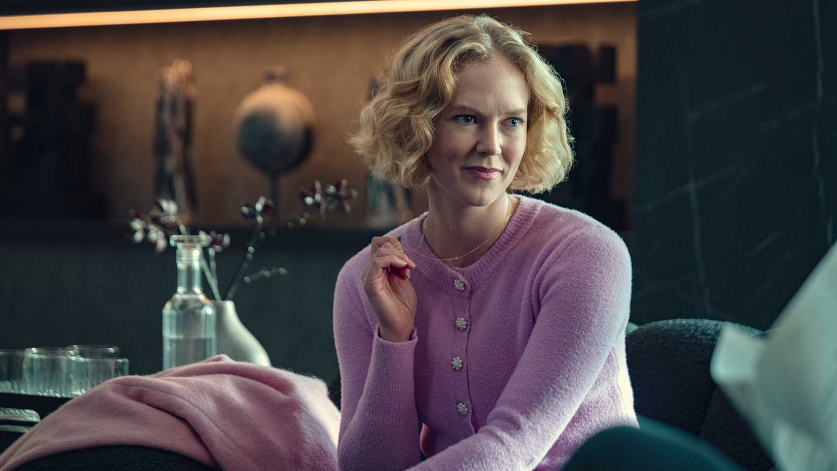 Verity in a pink sweater smiling mischievously in Black Mirror.