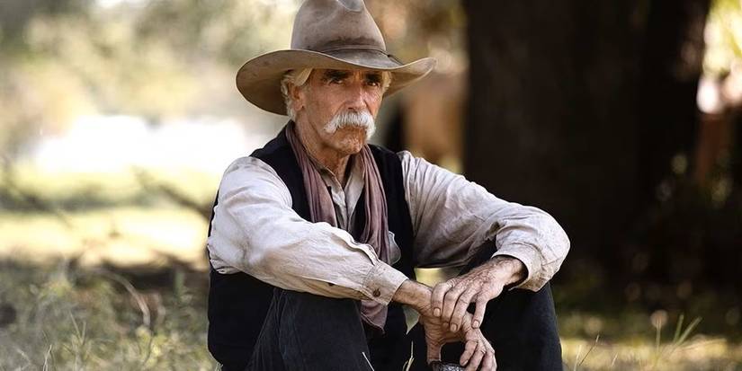 Sam Elliott in 1883 sitting down outside wearing cowboy gear
