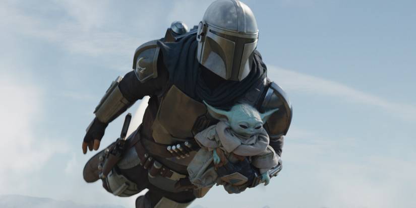 The Mandalorian holding on to Grogu while flying through the sky in The Mandalorian