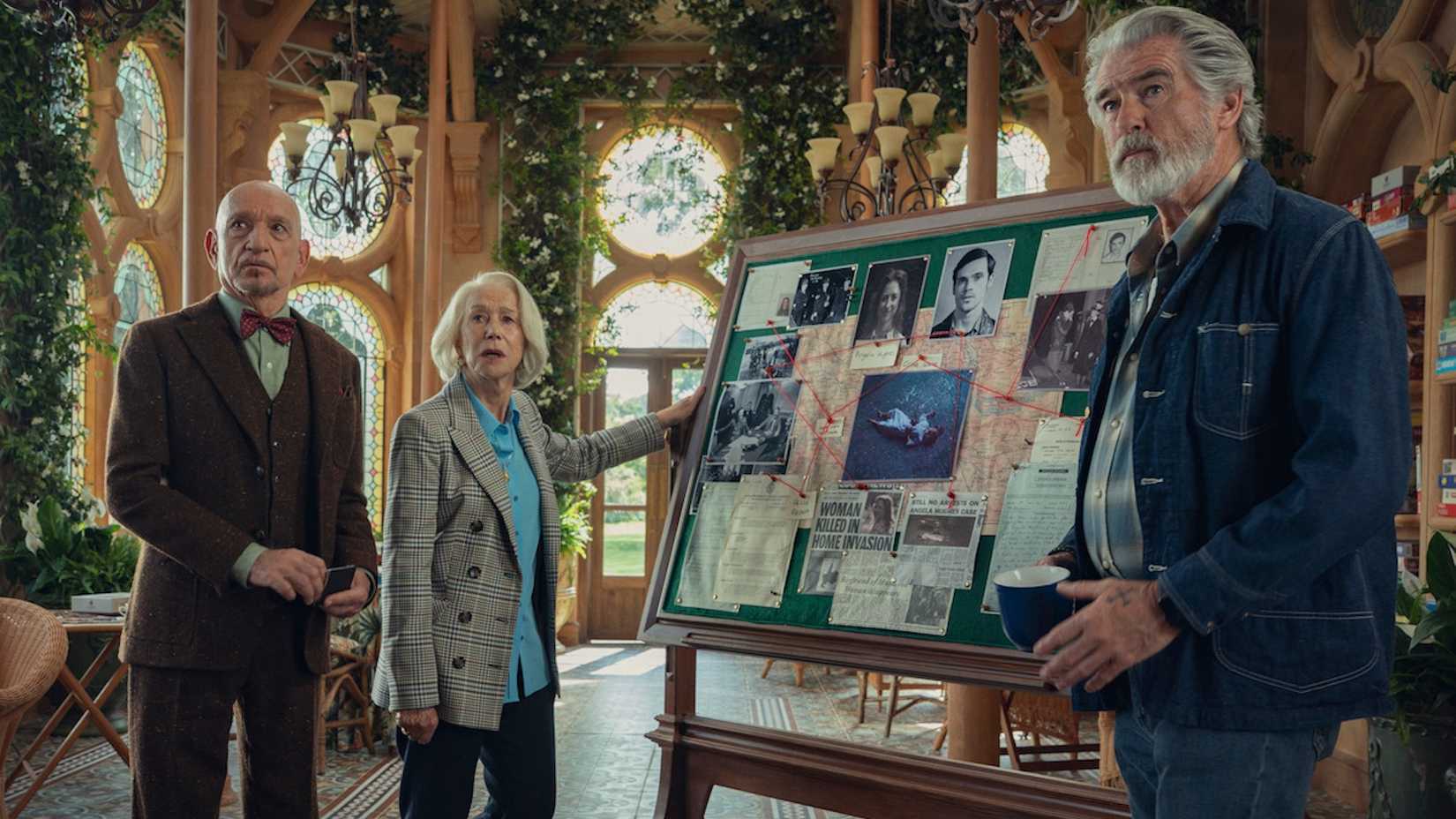 Ben Kingsley, Helen Mirren, and Pierce Brosnan examining evidence in The Thursday Murder Club