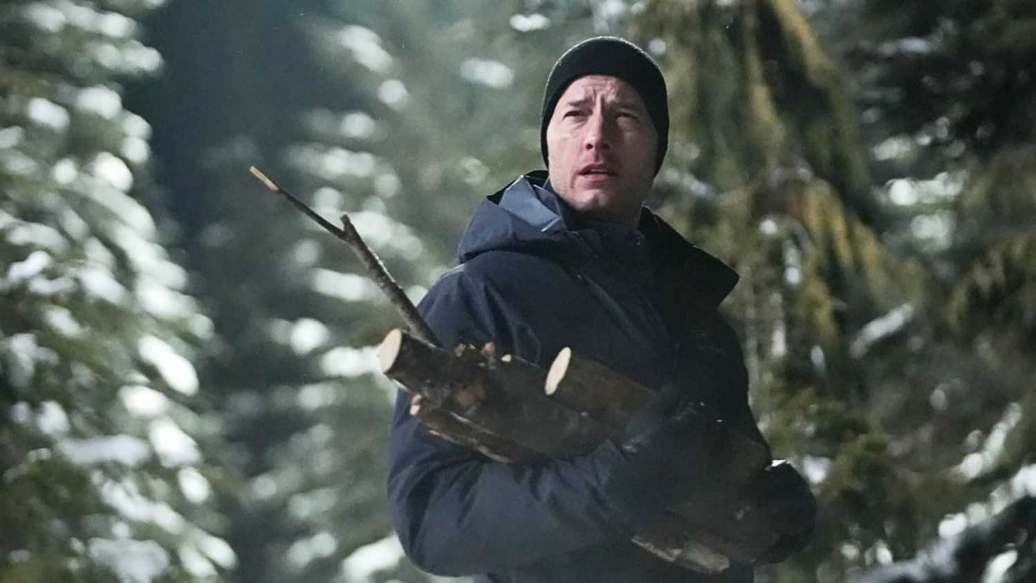 Colter in the wilderness holding firewood looking up in Tracker