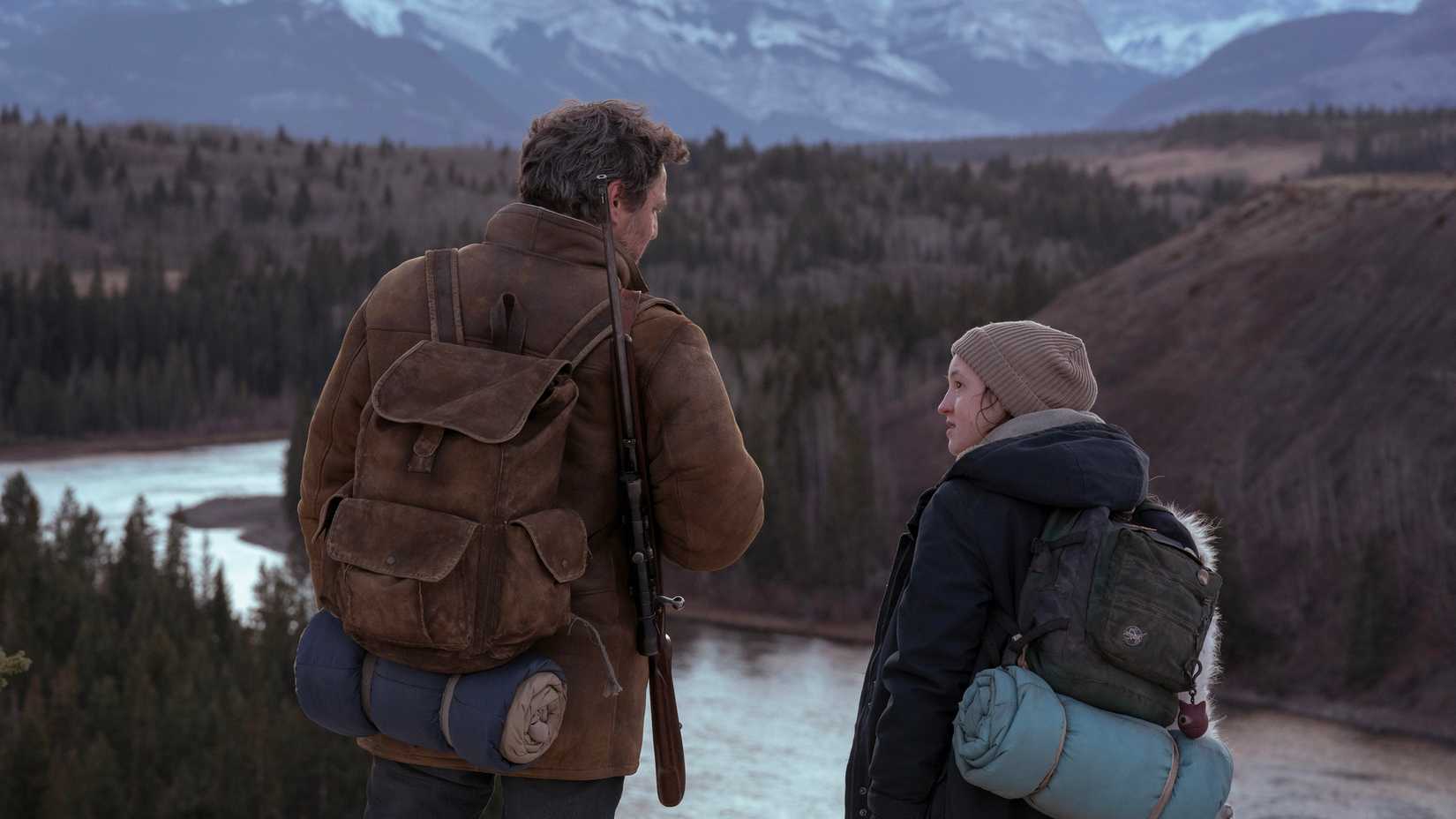 Joel and Ellie standing by the water with backpacks in The Last of Us