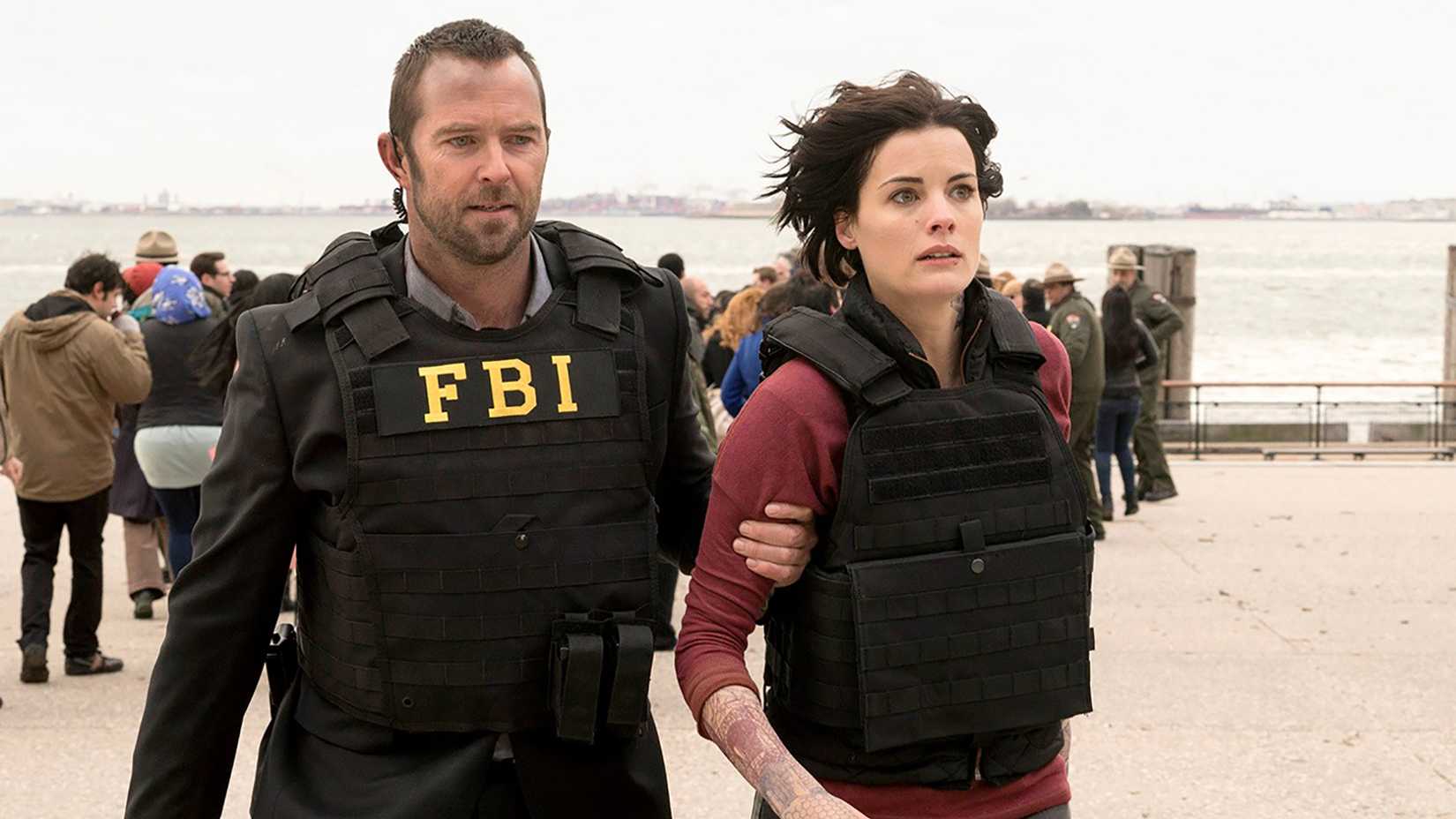 Kurt holding Jane by the arm, both wearing bulletproof vests, in Blindspot.