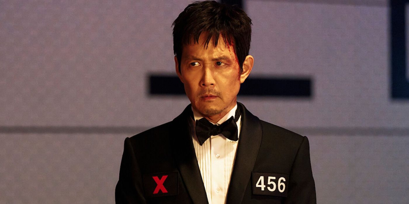 Lee Jung-jae as Seong Gi-hun/Player 456 wearing a suit with a red X on jacket in Squid Game Season 3 