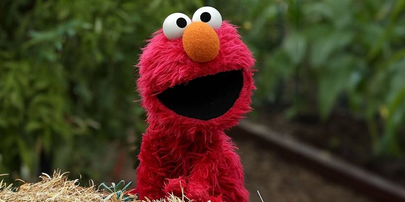 Elmo from Sesame Street, standing by some hay
